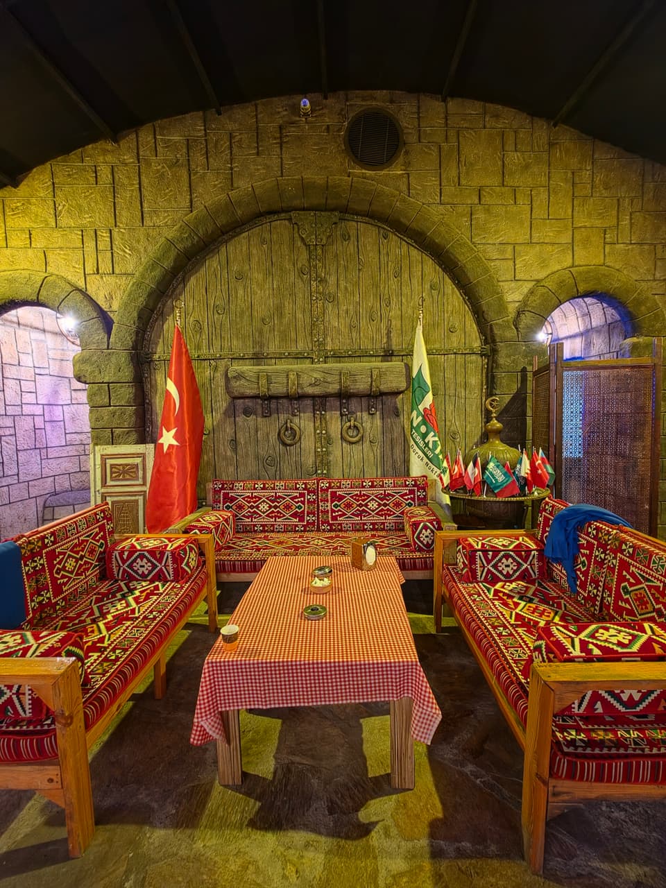 Taş duvarlı salonda kilim minderli şark köşesi